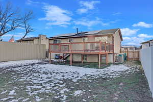 Snow covered house with a deck, central air condition unit, and solar panels