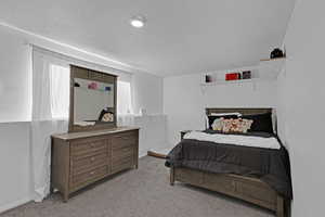 Bedroom featuring light carpet and a textured ceiling