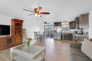 Living room featuring ceiling fan, a textured ceiling, and light wood-type flooring