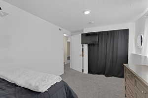 Bedroom featuring light carpet and a textured ceiling