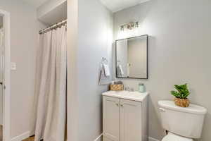 Bathroom featuring a shower with curtain, vanity, and toilet