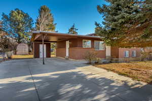 View of front of property with a carport and a shed