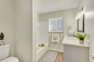 Bathroom featuring vanity, toilet, wood-type flooring, and a tub