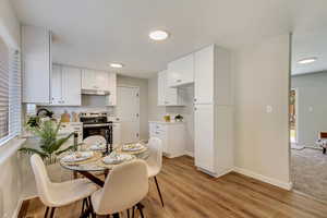 Kitchen featuring stainless steel electric stove, white cabinets, and light hardwood / wood-style floors