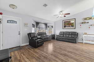 Living room with lofted ceiling, hardwood / wood-style flooring, and ceiling fan