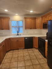 Kitchen featuring light tile patterned flooring, sink, a textured ceiling, and black appliances