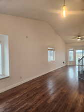 Unfurnished room with ceiling fan, lofted ceiling, and dark hardwood / wood-style flooring