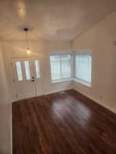 Foyer with dark hardwood / wood-style floors, vaulted ceiling, and a textured ceiling