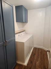 Laundry room featuring cabinets, washer and dryer, and dark hardwood / wood-style floors