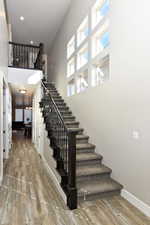 Stairs with hardwood / wood-style flooring and a high ceiling