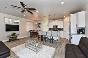 Living room with ceiling fan and light hardwood / wood-style floors