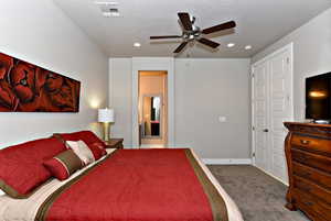 Carpeted bedroom with a textured ceiling and ceiling fan