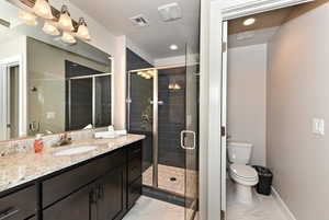 Bathroom with vanity, a shower with door, and toilet