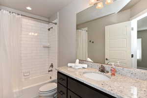 Full bathroom with vanity, shower / bath combination with curtain, and toilet