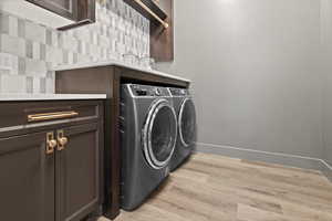 Washroom featuring cabinets, washing machine and clothes dryer, and light hardwood / wood-style floors