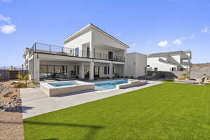 Rear view of house featuring a balcony, a lawn, a patio area, and a pool with hot tub