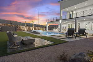 Pool at dusk with a fire pit, a patio, and an outdoor kitchen