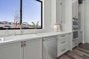 Kitchen with sink, white cabinets, dark hardwood / wood-style flooring, stainless steel appliances, and light stone countertops