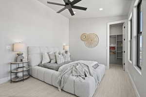 Bedroom featuring a walk in closet, light colored carpet, a closet, and ceiling fan