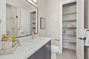 Bathroom featuring vanity, toilet, tile patterned floors, and a shower with shower door