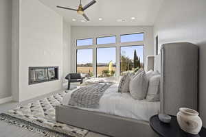 Bedroom featuring a tile fireplace, high vaulted ceiling, and ceiling fan