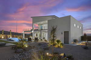 Back house at dusk featuring an outdoor hangout area, a patio area, and a balcony