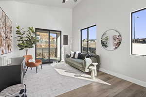 Living room featuring hardwood / wood-style floors, a towering ceiling, a healthy amount of sunlight, and ceiling fan