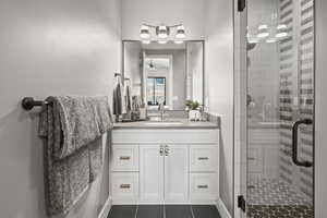 Bathroom featuring ceiling fan, vanity, tile patterned flooring, and a shower with door