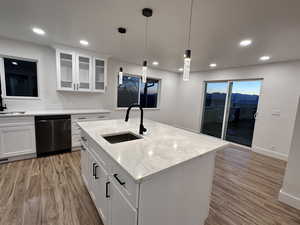 Kitchen with white cabinetry, black dishwasher, sink, and a center island with sink