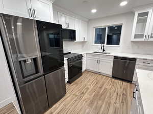 Kitchen featuring stainless steel appliances, sink, and white cabinets