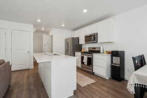 Kitchen featuring stainless steel appliances, an island with sink, sink, and white cabinets