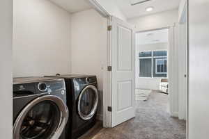 Laundry room featuring light colored carpet and independent washer and dryer