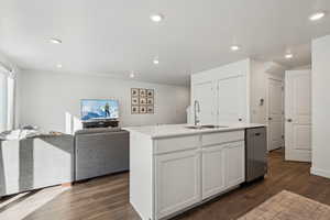 Kitchen featuring dark hardwood / wood-style floors, white cabinetry, dishwasher, sink, and a center island with sink