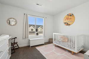 Carpeted bedroom featuring a crib