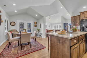 Dining space with vaulted ceiling, ceiling fan, light hardwood / wood-style floors, and sink