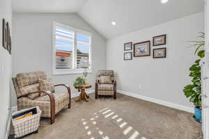 Sitting room featuring carpet floors and vaulted ceiling