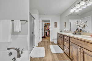 Bathroom featuring hardwood / wood-style flooring, vanity, toilet, and a shower with shower door