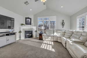 Carpeted living room with ceiling fan, a healthy amount of sunlight, and lofted ceiling