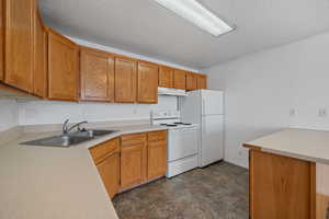 Kitchen with sink, white appliances, and a textured ceiling