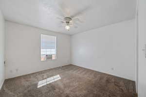 Spare room featuring cooling unit, a textured ceiling, ceiling fan, and carpet flooring