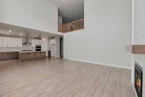 Unfurnished living room featuring a high ceiling and light hardwood / wood-style flooring