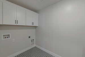 Clothes washing area featuring electric dryer hookup, washer hookup, and cabinets