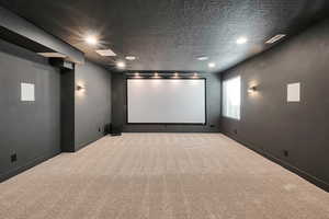 Home theater featuring a textured ceiling and carpet flooring