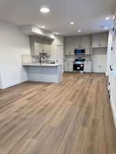 Kitchen featuring tasteful backsplash, gray cabinets, stainless steel appliances, and kitchen peninsula