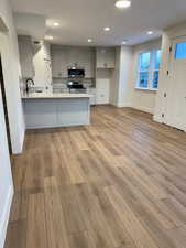 Kitchen with stainless steel appliances, kitchen peninsula, light hardwood / wood-style floors, and gray cabinetry