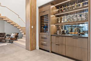 Bar featuring stairway, a sink, finished concrete floors, and wet bar