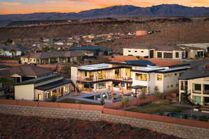 Back of house at dusk with stairway, a residential view, and a mountain view