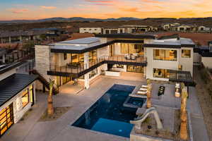 Back of property at dusk featuring a residential view, a pool with connected hot tub, a patio area, and a mountain view