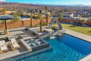 View of swimming pool with a fenced backyard, a residential view, a water slide, a pool with connected hot tub, and a mountain view