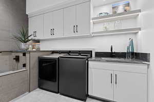 Laundry room featuring cabinet space, washer and clothes dryer, and a sink